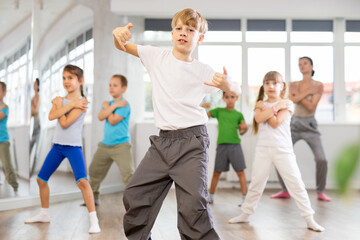 During dance workshop, boy with team of young like-minded children learn to dance modern dances,...