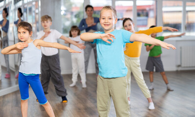 Fototapeta premium Children studying modern style dances with female teacher in dance class indoors