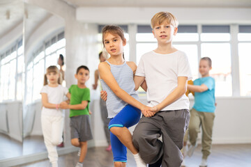 Young children couple learns to quickstep pair dance during dance class in studio, repeat movements and learn slow couple dance. Studio school for amateur and professional dancers