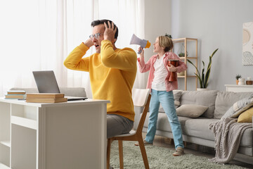 Working young man stressed of his noisy little son at home