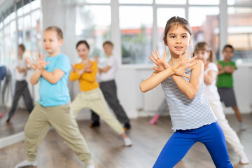 Girl learns to dance hip hop during childrens master class in studio. Teacher watches students,...
