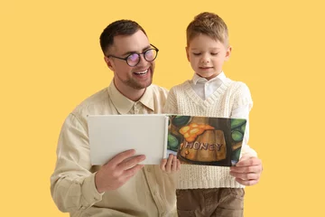 Foto op Canvas Happy father and his little son reading book together on yellow background © Pixel-Shot