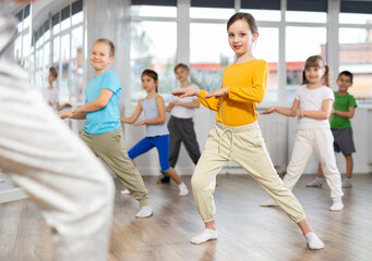 Happy positive smiling preteen boys and girls practicing dance, with female trainer in dance hall