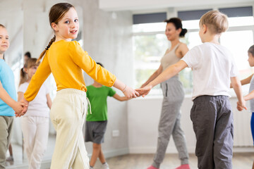 Children holding hands and dancing in a round dance in choreography class