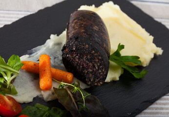 Black pudding with rice served with potato puree, vegetables and greens