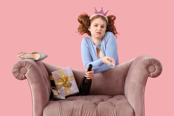 Young woman with hangover and champagne behind armchair after Birthday party on pink background