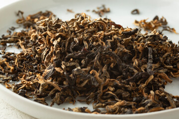 A closeup view of a pile of zhen qu golden buds loose leaf tea.
