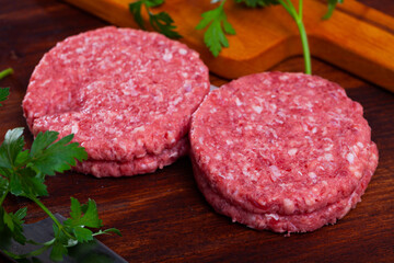 Raw handmade minced pork burgers patties on wooden table