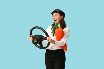 Happy female taxi driver with toy carrot and steering wheel on blue background. Easter celebration