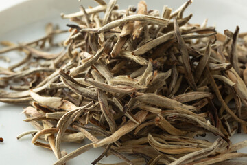 A closeup view of a pile of loose leaf yin zhen white tea.