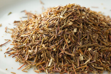 A closeup view of a pile of loose leaf green rooibos herbal tea.