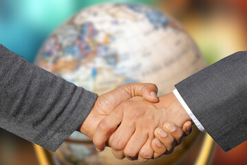 Ein Globus und ein Handschlag zwischen zwei Partnern