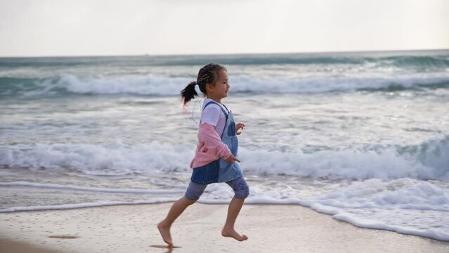 Slow motion 4k Clip of happy little asian girl running on the beach with barefoot at Wanning Hainan China 