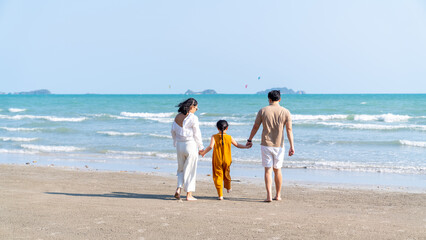 Fototapeta na wymiar Happy Asian family travel ocean on summer holiday vacation. Parents and little daughter girl enjoy and fun outdoor activity lifestyle walking and playing together on tropical island beach in sunny day