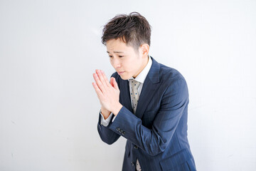 困り顔で合掌するビジネスマン