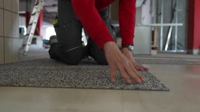 Carpet tiler man laying and installing carpet rug floor wall to wall