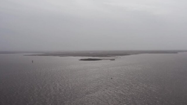 Wide aerial shot of historic Fort Sumter in Charleston Harbor from Fort Moultrie on Sullivan's Island during a gloomy day with low visibility in South Carolina. 4K