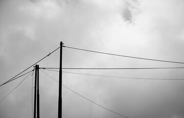 Electric poles with white clouds in the background during fog