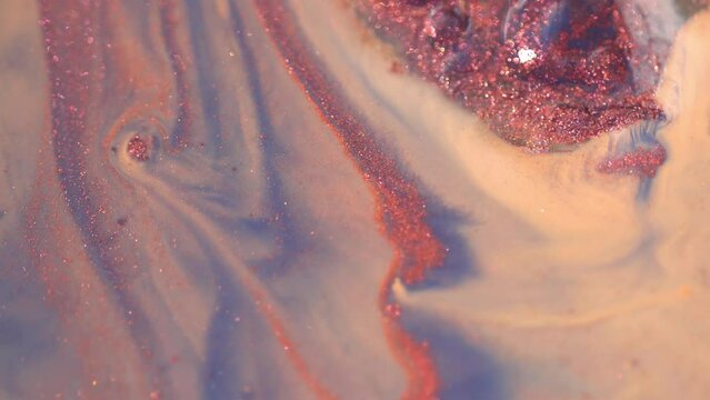 Pink and beige colors mix with glitter copper holographic particles. Paint movement macro. Ink flow. Glitter fluid motion. Moving flowing stream of liquid paint