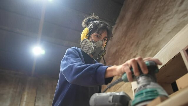 Woman carpenter sanding wood block. Feminist girl process timber bar. Male carpentry work skill. Female joiner woodwork. Feminism worker. Person use sander tool. Diy master class workshop. Job project