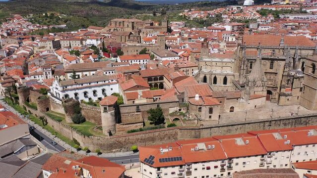 Drone view of picturesque cityscape of historical part of Placencia surrounded by ancient fortress wall overlooking tiled roofs of houses and medieval gothic cathedral on sunny spring day, Spain. High