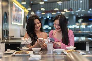 Two asian women selecting food , elegant restaurant, deeply engrossed in selecting meals from gourmet menu, lifestyle, leisure, luxury dining, female friendship, discussing sharing recommendation