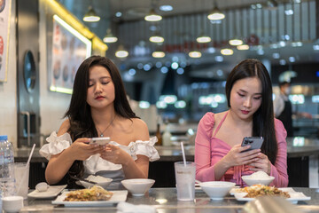 Two asian women selecting food , elegant restaurant, deeply engrossed in selecting meals from...