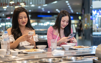 Two asian women selecting food , elegant restaurant, deeply engrossed in selecting meals from...