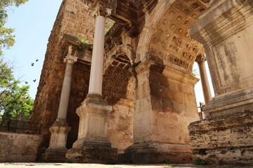 Fototapeta premium Pigeons landing on the wall next to the Hadrians Gate, famous ancient roman landmark in Antalya, Turkey