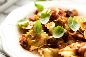 Ravioli with mushrooms and fresh basil. Bright wooden background. Close up.	