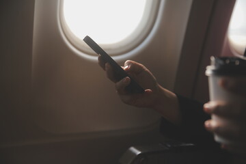 Blonde female tourist checking incoming notification on smartphone sitting on seat of airplane with...