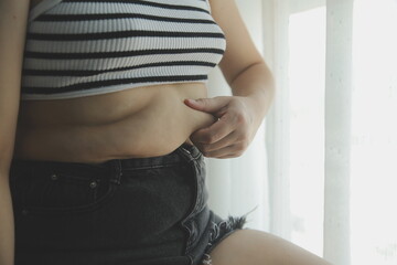 Women body fat belly. Obese woman hand holding excessive belly fat. diet lifestyle concept to reduce belly and shape up healthy stomach muscle. - obrazy, fototapety, plakaty