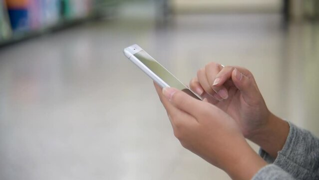 Close up Asian woman hands holding smartphone with E-commerce Shopping online website Reading Online E-book. Young reader Woman hands holding phone technology lifestyle finding book in smart library