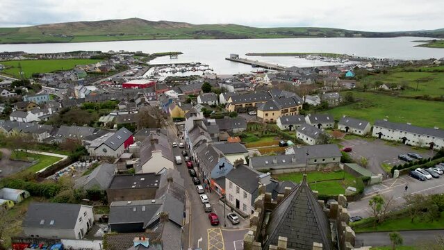 dramatic drone push past church in Dingle Ireland and flies down to boats in harbor on overcast day on peninsula