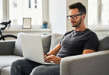 Man working from home sitting on sofa with laptop