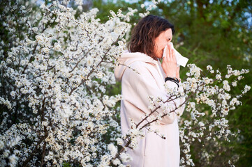 Man allergic suffering from seasonal allergy at spring in blossoming garden at springtime. Young...