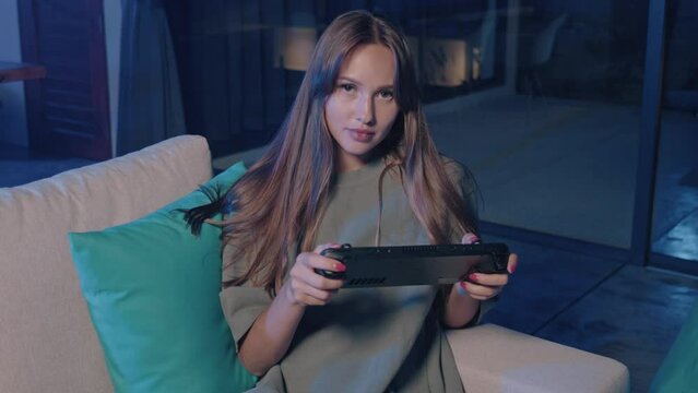 A woman sitting on a couch having fun playing a video game on a Nintendo Switch