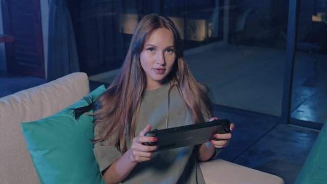 A woman sitting on a couch playing a video game on her Nintendo Switch