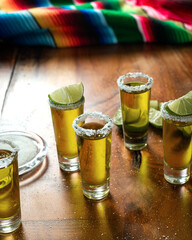 Shots of tequila with salt and lemon on a wooden table. Festive background cinco de mayo and...