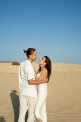 Vertical view of young couple looking to each other in sand dunes at the beach