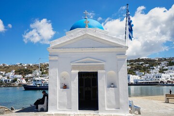 Miniature Greek Orthodox church in traditional Greek white and blue color scheme along the harbor of the Old Town in Mykonos, Greece