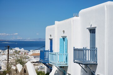 Homes of Mykonos with bright blue balconies overlooking the Old Town and Aegean Sea in Mykonos,...