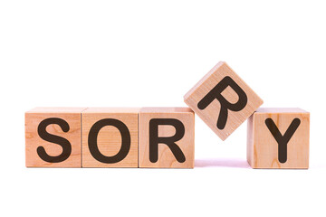 Word SORRY is made of wooden building blocks lying on the table and on a light background. Concept.