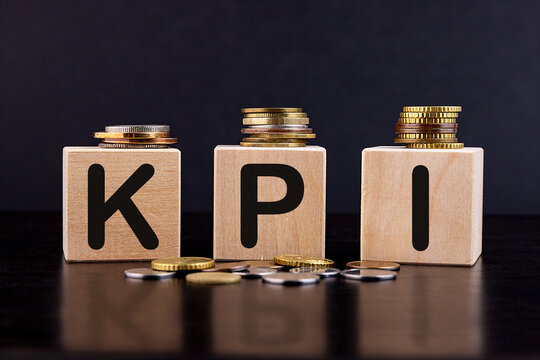 KPI Word Written In Wooden Blocks with coins around. Key Performance Indicator business concept.