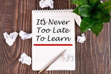 It's never too late to learn notepad writing concept on a wooden background with pen.