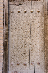 An ancient wooden door with patterns and ornaments in the ancient city of Khiva in Uzbekistan, wood carving