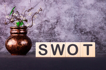 Word SWOT made with wooden building blocks on a gray back ground