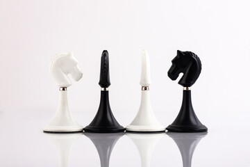 White and black chess pieces on a reflective surface. Business concept. Game, strategy, wisdom,...