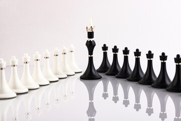 White and black chess pieces on a reflective surface. Business concept. Game, strategy, wisdom,...