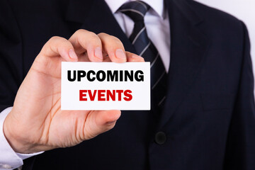 Businessman shows a sign with the text UPCOMING EVENTS. Business concept